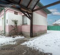 Na predaj 4-izbový rodinný dom, Gabčíkovo - Zasnežený dvor rodinného domu v Gabčíkove s ružovo-bielou fasádou a zelenou bránou.