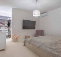 NA PREDAJ 4 IZB RD S DVOJGARÁŽOU, DUNAJSKÁ STREDA - Spálňa v rodinnom dome s televízorom, otvorenou skriňou a pohodlným kreslom.