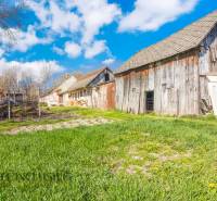 NA PREDAJ 4-IZBOVÝ RODINNÝ DOM NA PRIESTRANNOM POZEMKU - Staré budovy a trávnatá plocha v dedine, stromy, Rodinný dom, modrá obloha.