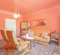 NA PREDAJ 4-IZBOVÝ RODINNÝ DOM NA PRIESTRANNOM POZEMKU - Interiér obývačky s oranžovými stenami, pohodlným nábytkom, lampami a nástenným zrkadlom. Rodinný dom.