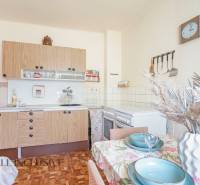 NA PREDAJ 4-IZBOVÝ RODINNÝ DOM NA PRIESTRANNOM POZEMKU - Kuchyňa v rodinnom dome s drevenými skrinkami, stolom a dekoráciou na vidiecku atmosféru.