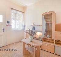 NA PREDAJ 4-IZBOVÝ RODINNÝ DOM NA PRIESTRANNOM POZEMKU - Obývacia izba rodinného domu s dreveným nábytkom a dekoratívnou vázou na stole.