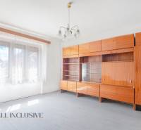 NA PREDAJ RODINNÝ DOM NA 9,5 ÁROVOM POZEMKU, OHRADY - Izba v rodinnom dome, drevená zostava nábytku, biele steny a závesy.