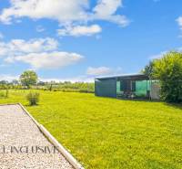 REZERVOVANÉ 3-IZBOVÝ RODINNÝ DOM V OBCI BALOŇ - Záhrada rodinného domu v Baloňi s udržiavaným trávnikom a prístreškom.