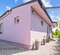 REZERVOVANÉ 3-IZBOVÝ RODINNÝ DOM V OBCI BALOŇ - Rodinný dom v Baloňi v svetlofialovej fasáde so štrkovým chodníkom a kvetináčmi.