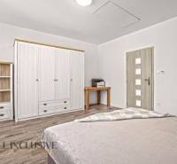 REZERVOVANÉ 3-IZBOVÝ RODINNÝ DOM V OBCI BALOŇ - Spálňa v rodinnom dome so skriňou, poličkou, stolíkom a podlahou s dreveným dekorom.