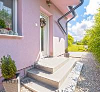 REZERVOVANÉ 3-IZBOVÝ RODINNÝ DOM V OBCI BALOŇ - Rodinný dom v Baloni s ružovou fasádou, bielymi dverami a kvetinovým dekorom.