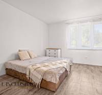 REZERVOVANÉ 3-IZBOVÝ RODINNÝ DOM V OBCI BALOŇ - Svetlá spálňa s posteľou, komodou a podlahou s dreveným dekorom v rodinnom dome.