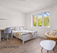 REZERVOVANÉ 3-IZBOVÝ RODINNÝ DOM V OBCI BALOŇ - Svetlá spálňa s posteľou, stolom a podlahou s dreveným dekorom v rodinnom dome.