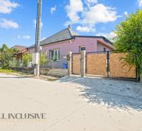 REZERVOVANÉ 3-IZBOVÝ RODINNÝ DOM V OBCI BALOŇ - Rodinný dom v Baloňi s ružovou fasádou, plotom a zelenou vegetáciou v okolí.
