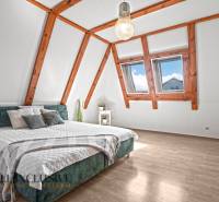 REZERVOVANÉ ZREKONŠTR. 6 IZBOVÝ RODINNÝ DOM, KOŠÚTY - Podkrovná spálňa v rodinnom dome s posteľou a podlahou s dreveným dekorom.