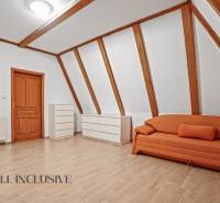 REZERVOVANÉ ZREKONŠTR. 6 IZBOVÝ RODINNÝ DOM, KOŠÚTY - Izba v rodinnom dome s oranžovou sedačkou, bielymi komodami a podlahou s dreveným dekorom.