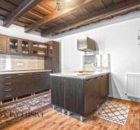 REZERVOVANÉ ZREKONŠTR. 6 IZBOVÝ RODINNÝ DOM, KOŠÚTY - Kuchyňa v rodinnom dome s dreveným stropom, tmavými skrinkami a podlahou s dreveným dekorom.