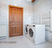 REZERVOVANÉ ZREKONŠTR. 6 IZBOVÝ RODINNÝ DOM, KOŠÚTY - Práčka, sušička, drevené poličky a radiator v kúpeľni rodinného domu.