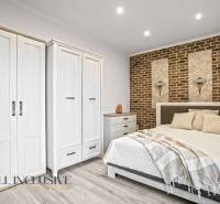 NA PREDAJ 4-IZB NOVOSTAVBA S TROJGARÁŽOU, PIN. KRAČANY - Spálňa v rodinnom dome s posteľou, bielymi skriňami a tehlovou stenou.