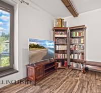 NA PREDAJ 4-IZB NOVOSTAVBA S TROJGARÁŽOU, PIN. KRAČANY - Obývacia izba v rodinnom dome s TV, knihovňou a podlahou s dreveným dekorom.