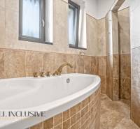 NA PREDAJ 4-IZB NOVOSTAVBA S TROJGARÁŽOU, PIN. KRAČANY - Kúpeľňa v rodinnom dome s veľkou vaňou a obkladačkami v drevenom dekore.