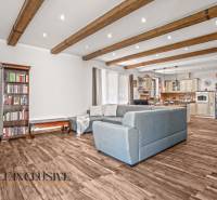 NA PREDAJ 4-IZB NOVOSTAVBA S TROJGARÁŽOU, PIN. KRAČANY - Obývacia izba v rodinnom dome s podlahou s dreveným dekorom, pohodlnou sedačkou a knižnicou.