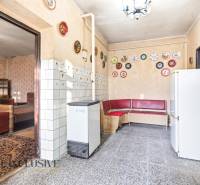 Na predaj 4-izbový rodinný dom, Dolné Saliby - Interiér rodinného domu s červenou rohovou lavicou, dlaždicami a ozdobnými taniermi na stenách.