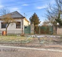 Na predaj 4-izbový rodinný dom, Dolné Saliby - Rodinný dom v Dolných Salibách s veľkou bránou a stromami pred domom.