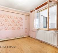 Na predaj 3-izbový rodinný dom, Dobrohošť - Izba v rodinnom dome s podlahou s dreveným dekorom a ružovými stenami.