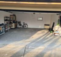 Na predaj 5-izb. rodinný dom na 50-á pozemku, Sap - Garáž v rodinnom dome v Sape s bicyklom, nástrojmi a úložnými regálmi.