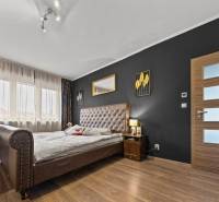 Na predaj 5-izb. rodinný dom na 50-á pozemku, Sap - Spálňa v rodinnom dome s tmavou stenou, veľkou posteľou a podlahou s dreveným dekorom.