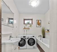 Na predaj 5-izb. rodinný dom na 50-á pozemku, Sap - Kúpeľňa v rodinnom dome s vaňou, práčkou a sušičkou, dekorovaná rastlinami.