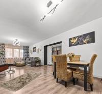 Na predaj 5-izb. rodinný dom na 50-á pozemku, Sap - Rodinný dom s podlahou s dreveným dekorom, ratanovým nábytkom a osvetlením v obývačke.