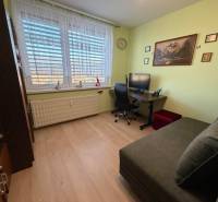 3 izbový byt s balkónom Topoľčany  - Izba s podlahou s dreveným dekorom v 3-izbovom byte, vybavená gaučom a pracovným stolom.