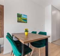 | Krásny a moderný 2-izbový byt | 51,50m² | - Jedálenský kút s dreveným stolom, zelenými stoličkami a podlahou s dreveným dekorom v 2-izbovom byte.
