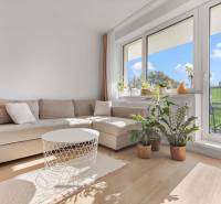 | Krásny a moderný 2-izbový byt | 51,50m² | - Obývačka v 2-izbovom byte s pohovkou, rastlinami a balkónom, podlaha s dreveným dekorom.