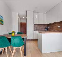 | Krásny a moderný 2-izbový byt | 51,50m² | - Kuchyňa v 2-izbovom byte s jedálenským stolom, zelenými stoličkami a podlahou s dreveným dekorom.