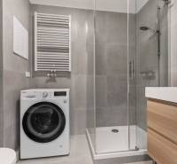 | Krásny a moderný 2-izbový byt | 51,50m² | - Kúpeľňa v 2-izbovom byte so sprchovým kútom, práčkou a umývadlom na drevenej skrinke.