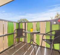 | Krásny a moderný 2-izbový byt | 51,50m² | - Balkón v 2-izbovom byte s ratanovými stoličkami a stolíkom, zelené drevené zábradlie.