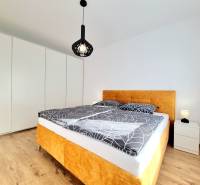 Posledný investičný krásny 2-izbový byt | 62 m² | RÍNOK RAČA - Spálňa v 2-izbovom byte s posteľou, bielymi stenami a podlahou s dreveným dekorom.