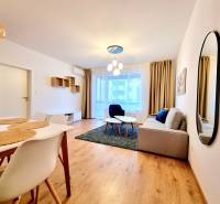 Posledný investičný krásny 2-izbový byt | 62 m² | RÍNOK RAČA - Obývačka v 2-izbovom byte s podlahou s dreveným dekorom, pohodlnou sedačkou a jedálenským stolom.