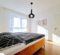 Posledný investičný krásny 2-izbový byt | 62 m² | RÍNOK RAČA - Spálňa s dvojlôžkom, bielymi závesmi a podlahou s dreveným dekorom v 2-izbovom byte.