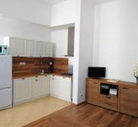 Predaj - štýlový 2i byt  v srdci Starého Mesta - Marianska, BA - Kuchynka v 2-izbovom byte, svetlý interiér, podlaha s dreveným dekorom, biela chladnička.