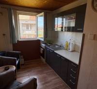 Útulný rodinný dom v tichej lokalite Mýtnych Ludán (MK-4) - Kuchyňa s podlahou s dreveným dekorom a tmavými skriňami v rodinnom dome.