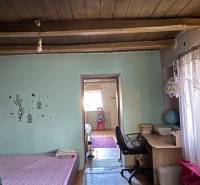 Útulný rodinný dom v tichej lokalite Mýtnych Ludán (MK-4) - Izba s podlahou s dreveným dekorom, posteľou, pracovným stolom a dekoračnými trámami na strope.