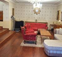 Luxusný rodinný dom s bazénom a dvojgarážou v Komárne - Obývacia izba v rodinnom dome s červeným nábytkom a televízorom na podlahe s dreveným dekorom.