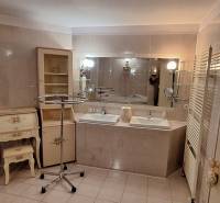 Luxusný rodinný dom s bazénom a dvojgarážou v Komárne - Kúpeľňa v rodinnom dome s dvomi umývadlami, zrkadlom a zdobeným nábytkom.