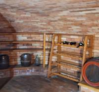 Luxusný rodinný dom s bazénom a dvojgarážou v Komárne - Vínna pivnica s tehlovými stenami a sudmi v rodinnom dome.