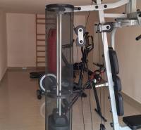 Luxusný rodinný dom s bazénom a dvojgarážou v Komárne - Fitness miestnosť s posilňovacími strojmi v rodinnom dome má svetlý keramický povrch.