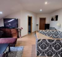 Luxusný rodinný dom s bazénom a dvojgarážou v Komárne - Obývacia izba v rodinnom dome s pohovkou, vzorovanou tapetou a TV.