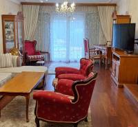 Luxusný rodinný dom s bazénom a dvojgarážou v Komárne - Obývacia izba v rodinnom dome s červenými kreslami a podlahou s dreveným dekorom.