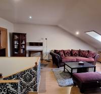 Luxusný rodinný dom s bazénom a dvojgarážou v Komárne - Obývacia izba s pohovkami a vzorovanými stenami, podlaha s dreveným dekorom.