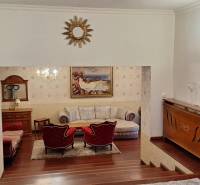 Luxusný rodinný dom s bazénom a dvojgarážou v Komárne - Luxusný interiér rodinného domu s dreveným dekorom, pohovkou a umeleckými dielami na stenách.