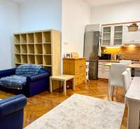 REZERVOVANÉ Na prenájom 3 izbový byt, 73 m2, Bratislava, Zochova - Obývacia izba 3-izbového bytu s kuchynským kútom, podlahou s dreveným dekorom a sedačkou.